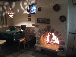 A cozy room with a fireplace, a television mounted on the wall, a pool table, and a comfortable seating area. - First class 2 room apartment, 2-4 people, close to the center of congress (Graubünden)