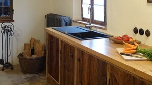 A kitchen with a wooden countertop, a sink, a window, and a radiator.