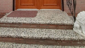 Eine hölzerne Doppeltür mit Glasscheiben, eine Ziegelwand und ein Metallgeländer.