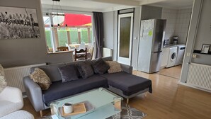 Una sala moderna con una mesa de centro de vidrio, un sofá gris y una zona de comedor con un paraguas rojo.