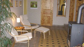Ein Zimmer mit zwei Lounge-Sesseln, einem kleinen Tisch, einem Heizgerät und einer Uhr an der Wand.