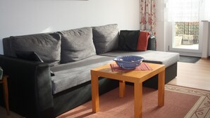 A living room with a grey sofa, a wooden coffee table, and a painting on the wall. - Middle row house near the beach, quiet location but in the middle of life (Butjadingen)