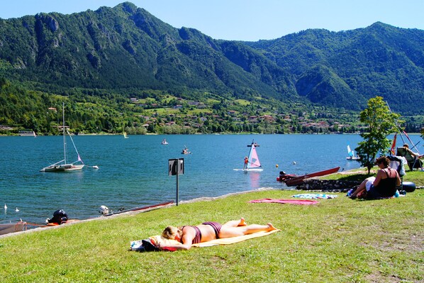 A lakeside view with boats, a woman sunbathing, and a mountainous backdrop. - Directly from the owner (Tre Capitelli)