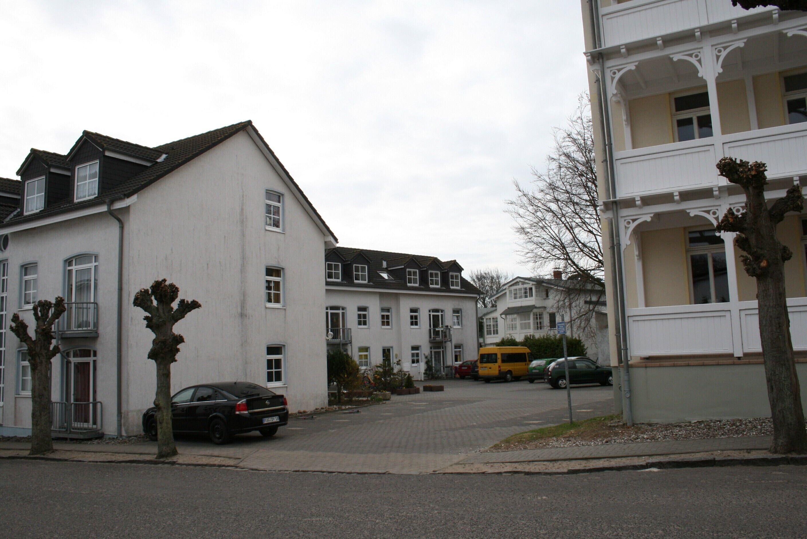 Eine Wohnstraße mit Häusern, parkenden Autos und einem gelben Bus.