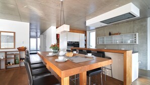 A modern kitchen with a wooden island, black bar stools, and a built-in refrigerator. - LOFT Rebhalde in Nonnenhorn on Lake Constance offers relaxation and comfort at the same time (Nonnenhorn)