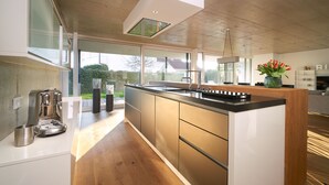 A modern kitchen with a large island, built-in appliances, and a view of the outdoors. - LOFT Rebhalde in Nonnenhorn on Lake Constance offers relaxation and comfort at the same time (Nonnenhorn)