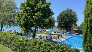 A swimming pool surrounded by lush greenery and a clear blue sky. - LOFT Rebhalde in Nonnenhorn on Lake Constance offers relaxation and comfort at the same time (Nonnenhorn)