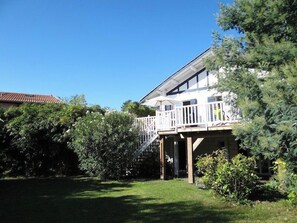 A two-story house with a balcony, surrounded by greenery. - Wonderful villa with idyllic garden A0338 (Lège-Cap-Ferret)