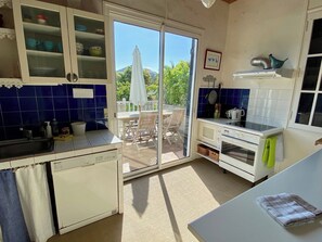 A kitchen with a sliding glass door leading to an outdoor patio area. - Wonderful villa with idyllic garden A0338 (Lège-Cap-Ferret)
