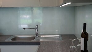A modern kitchen with a stainless steel sink, a built-in stove, and a wine bottle on the counter. - FeWo Betz Bodensee in Überlingen (Überlingen)