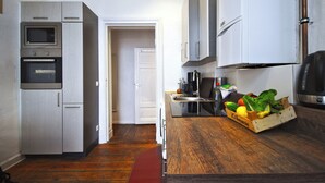 A compact kitchen with built-in appliances, a wooden countertop, and a door leading to another room. - Renovated old apartment with shower room, separate eat-in kitchen and washing machine (Berlin)