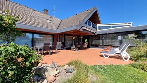 Una casa moderna con patio, arredi da esterno e piscina.