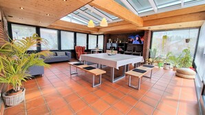 Un'area pranzo moderna con un tavolo grande, panche e una TV sullo sfondo.