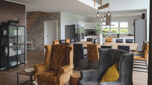 Un salón amplio con techo alto, una cocina al fondo y un comedor con muebles modernos.