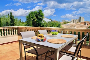 An outdoor dining area with a table, chairs, and a bowl of fruit.