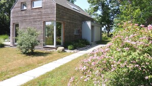 Una casa moderna de dos pisos con techo inclinado, ventanas amplias y un pequeño porche.
