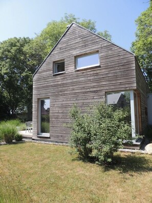 Une maison moderne avec un toit en pente, deux fenêtres et une porte d’entrée.