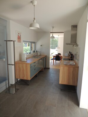 A modern kitchen with wooden cabinetry, a central island, and a dining area with a table and chairs.