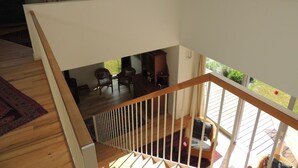 Un loft amplio con techo alto, escalera de madera y vista al patio trasero.