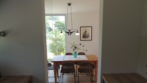 Un comedor con mesa de madera, sillas de mimbre y una lámpara colgante.