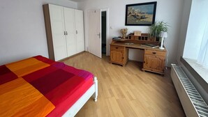 Une chambre à coucher avec un lit, un bureau, une armoire et une fenêtre.