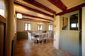A dining area with a wooden table and chairs, a chandelier, and a green door. - Exclusive 4-star holiday home for 8-12 people on historic Dreiseithof (Pirna)
