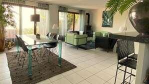 A modern living room with a dining area, green sofa, and a fireplace.
