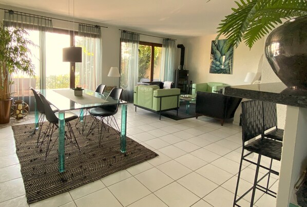 A modern living room with a dining area, green sofa, and a fireplace. - CASA GUSTO, vacation home with large garden terrace and wonderful lake view (Brissago TI)