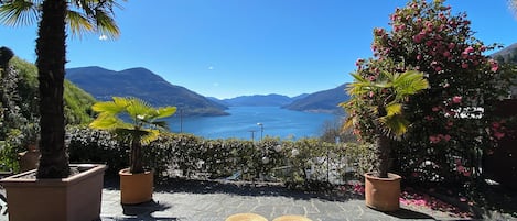 En terrasse med siddepladser, plantekasser og hav- og bjergudsigt.