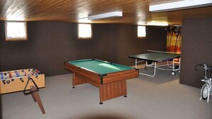 A room with a pool table, foosball table, and ping pong table.
