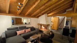 A cozy living room with a fireplace, a sofa, a coffee table, and a mirror on the wall.