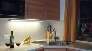 A kitchen with wooden cabinets, a stainless steel sink, and a fruit bowl containing bananas and apples. - Luxury 10 people hpuse near to a lift and loipe, 1700 m high (Krimml)