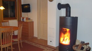 A cozy room with a wood-burning stove, wooden furniture, and a television on the wall. - Luxury 10 people hpuse near to a lift and loipe, 1700 m high (Krimml)