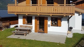 A two-story wooden chalet with a balcony, a wooden deck, and a mountain backdrop. - Luxury 10 people hpuse near to a lift and loipe, 1700 m high (Krimml)