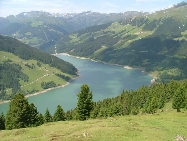 Une vue panoramique d’un lac entouré de collines boisées.