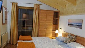 A bedroom with a large bed, wooden wardrobe, and a view of the outdoors through a window. - Luxury 10 people hpuse near to a lift and loipe, 1700 m high (Krimml)