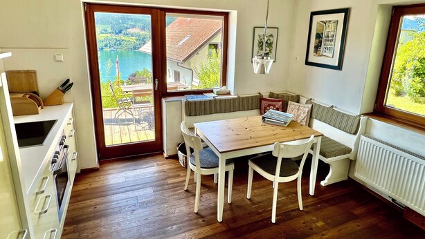 Cocina acogedora con suelo de madera, una mesa de comedor y vistas a un lago a través de puertas correderas de vidrio.