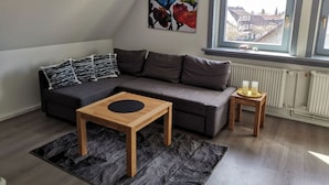 Una sala moderna con un sofá gris, una mesa de centro de madera y una mesita auxiliar con velas.