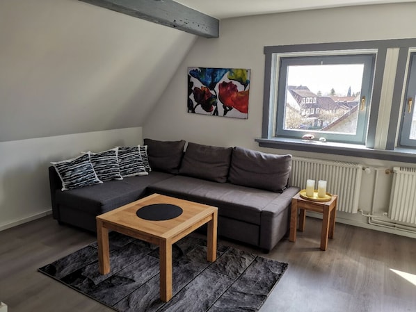 A modern living room with a grey sofa, a wooden coffee table, and a small side table with candles.