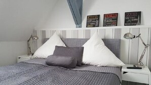 Un dormitorio con una cama, dos mesitas de noche y decoración en las paredes.