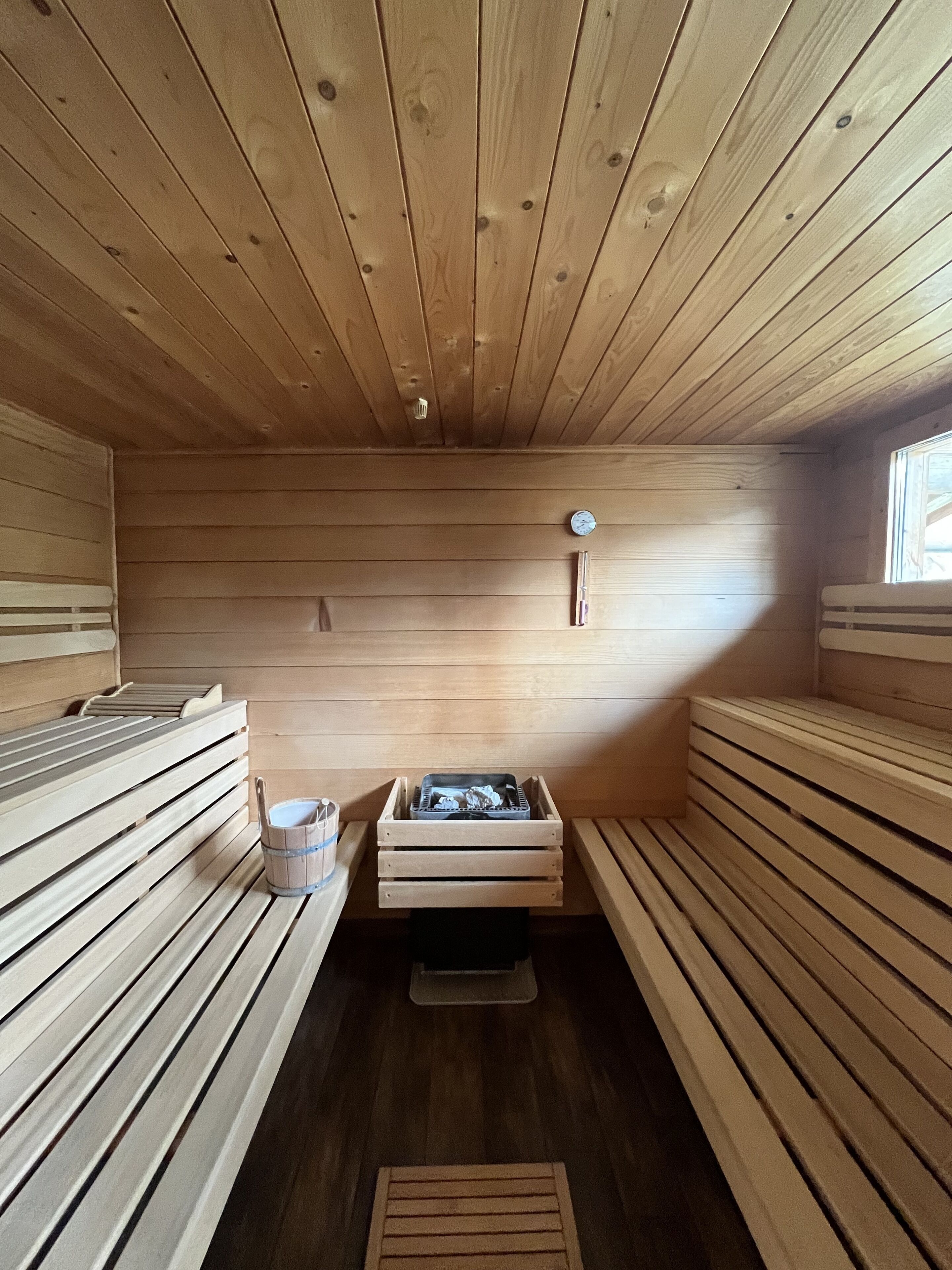 Ein Saunaraum mit Holzbänken und einer kleinen Holzablage.
