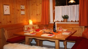 Ein Esszimmer aus Holz mit einem Tisch, gedeckt für zwei Personen, mit Kerze, Weingläsern und einem Brot.