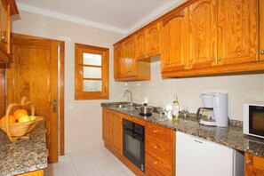 Compact kitchen with dishwasher and microwave, featuring a classic design and natural light.