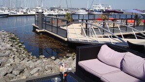 A marina with boats docked, a covered seating area with a cushion, and a metal railing. - «Het Fitschhuisje» Cozy cottage in the park "De Kreek" - Free Wi-Fi (Bruinisse)