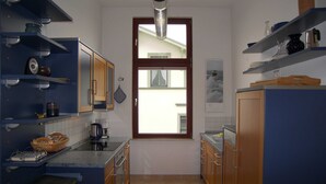 A compact kitchen with blue cabinetry, a coffee maker, and a window with a view of the outside. - Villa Medici Apartment 5 (Heringsdorf)