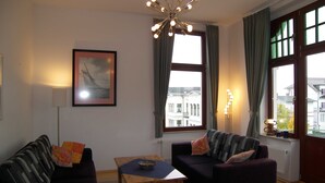 A living room with a sofa, a coffee table, and a painting on the wall. - Villa Medici Apartment 5 (Heringsdorf)