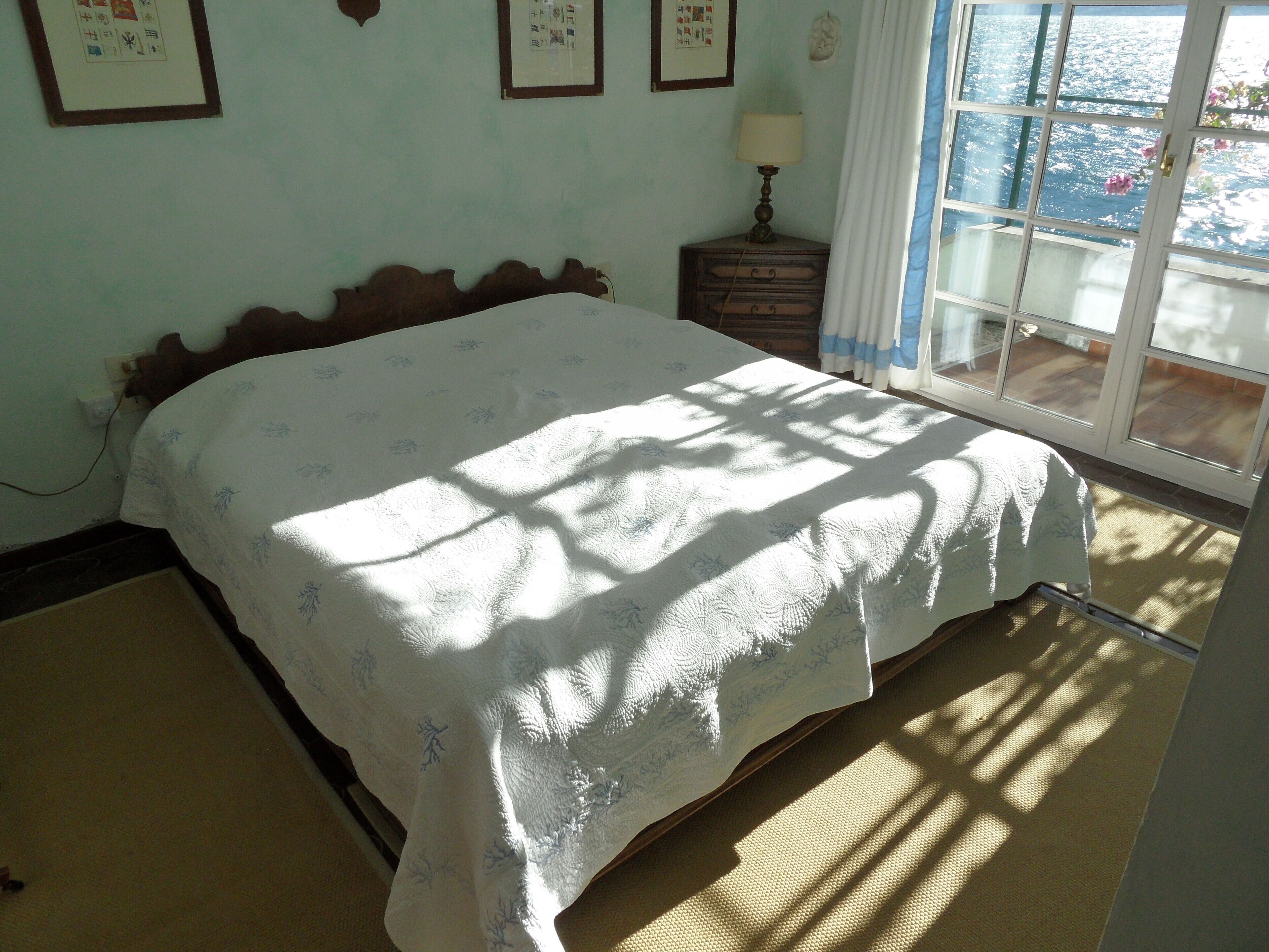A bedroom with a bed, a nightstand, a lamp, and a window with curtains.