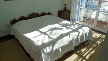 A bedroom with a bed, a nightstand, a lamp, and a window with curtains.