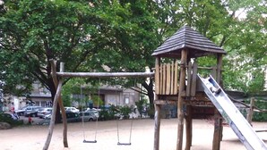 A playground with a wooden play structure, including a slide and swings. - Central and quiet - a view of the countryside (Berlin)