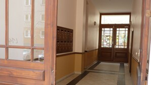 A hallway with wooden doors, a tiled floor, and a row of lockers on the wall. - Central and quiet - a view of the countryside (Berlin)
